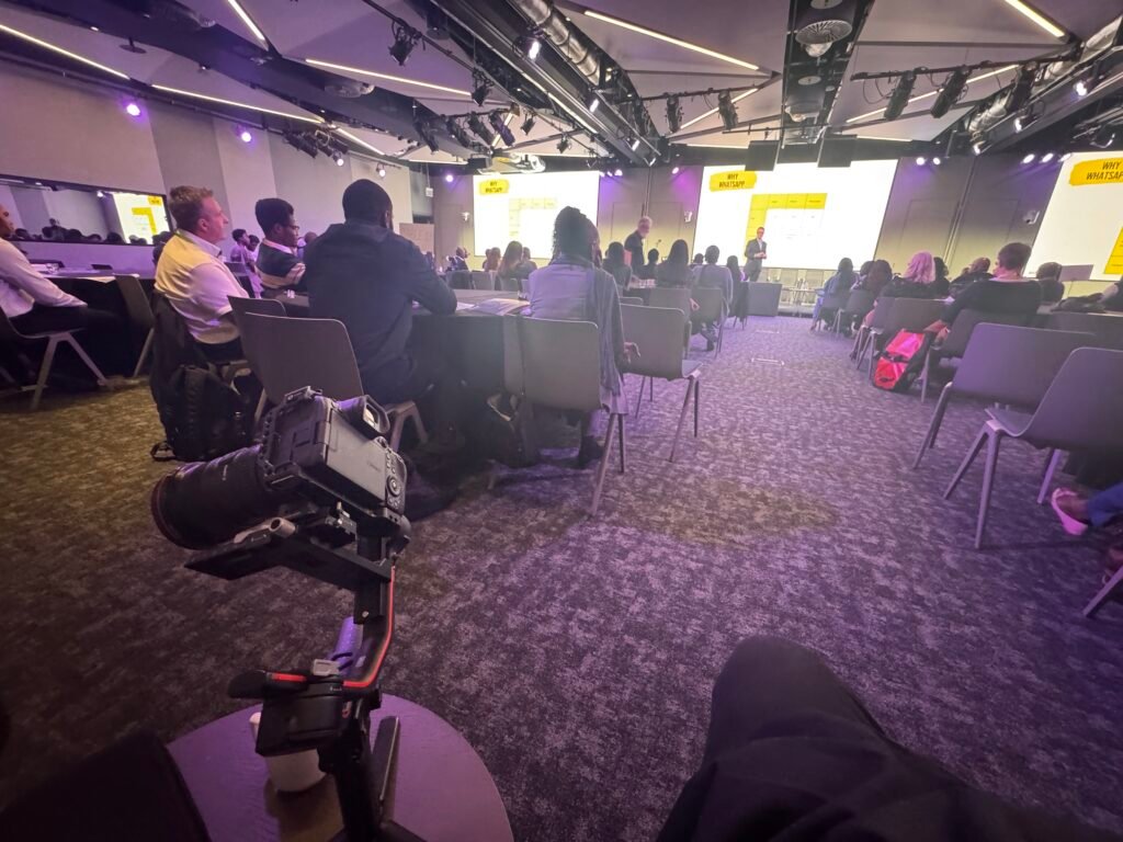 A speaker on stage being filmed by BridgeGap Media